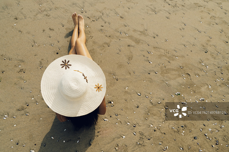 戴着帽子的女人躺在沙滩上图片素材