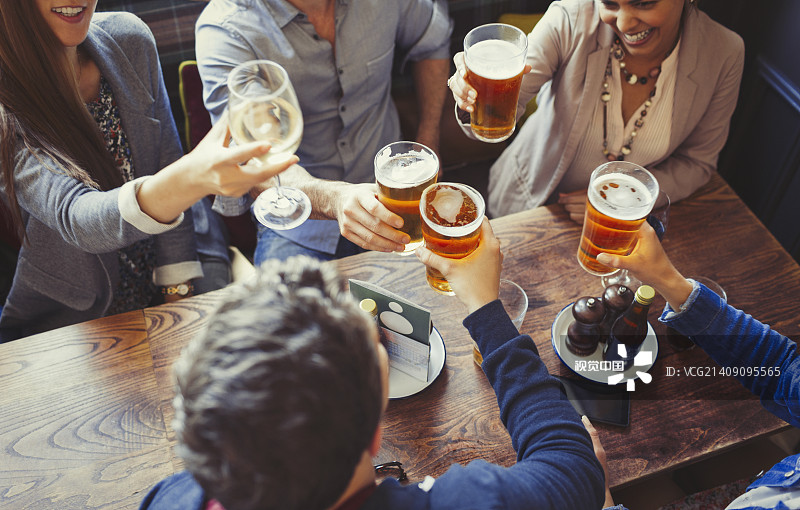 俯瞰朋友們在酒吧的餐桌上慶祝，舉杯互敬啤酒圖片素材
