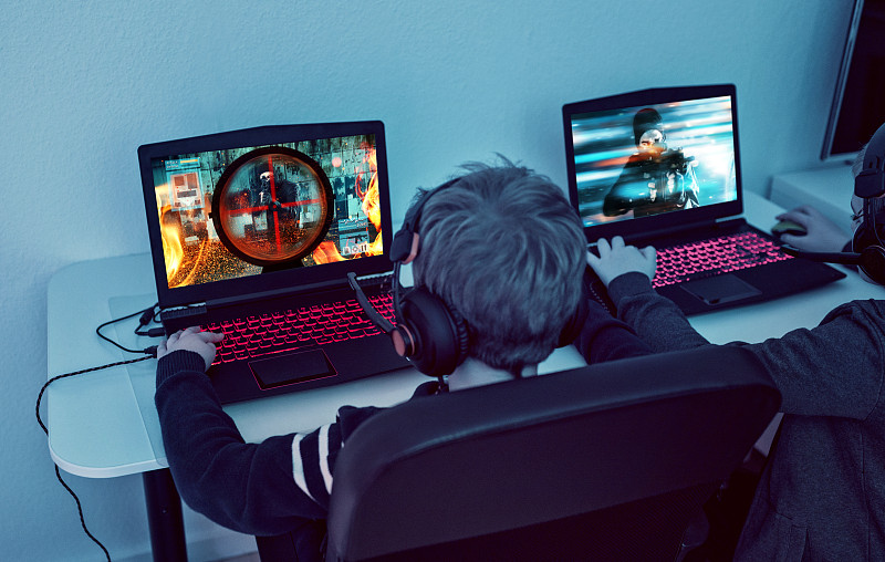 孩子們晚上在筆記本電腦上玩電子競技游戲的后視圖圖片素材