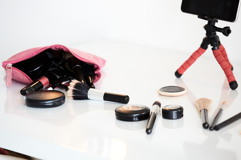 一個化妝博客的靜態生活設備放在桌子上，像化妝品，遮瑕膏和刷子圖片素材