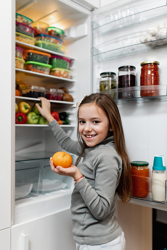 從冰箱里拿生食物的女孩圖片素材