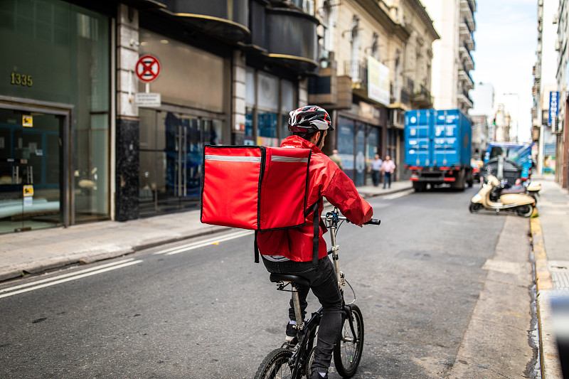 披薩外賣員在城市街道上騎自行車圖片素材