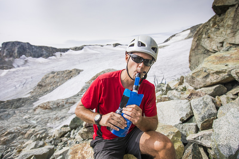 登山者從裝有過濾器的瓶子里喝水。圖片素材