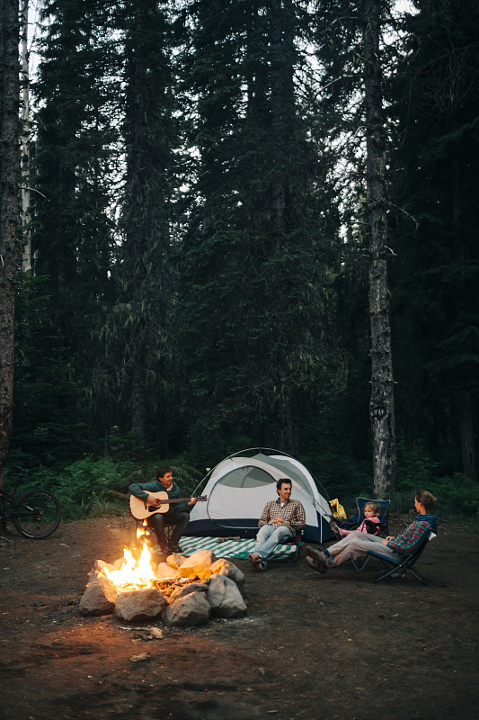 在俄勒岡州露營時，一群朋友圍坐在篝火旁。圖片下載