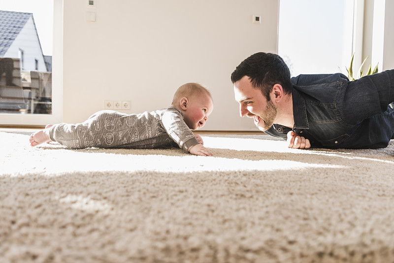 爸爸和小寶寶在地毯上玩爬圖片素材