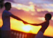 一对牵手的情侣的剪影在夕阳中模糊了图片素材