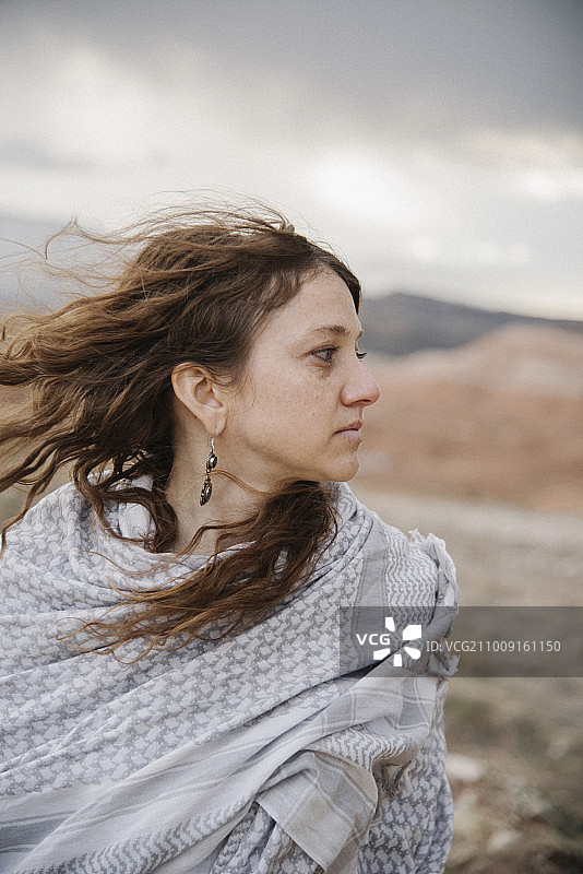 一位长发飘飘的女子站在沙漠中。图片素材