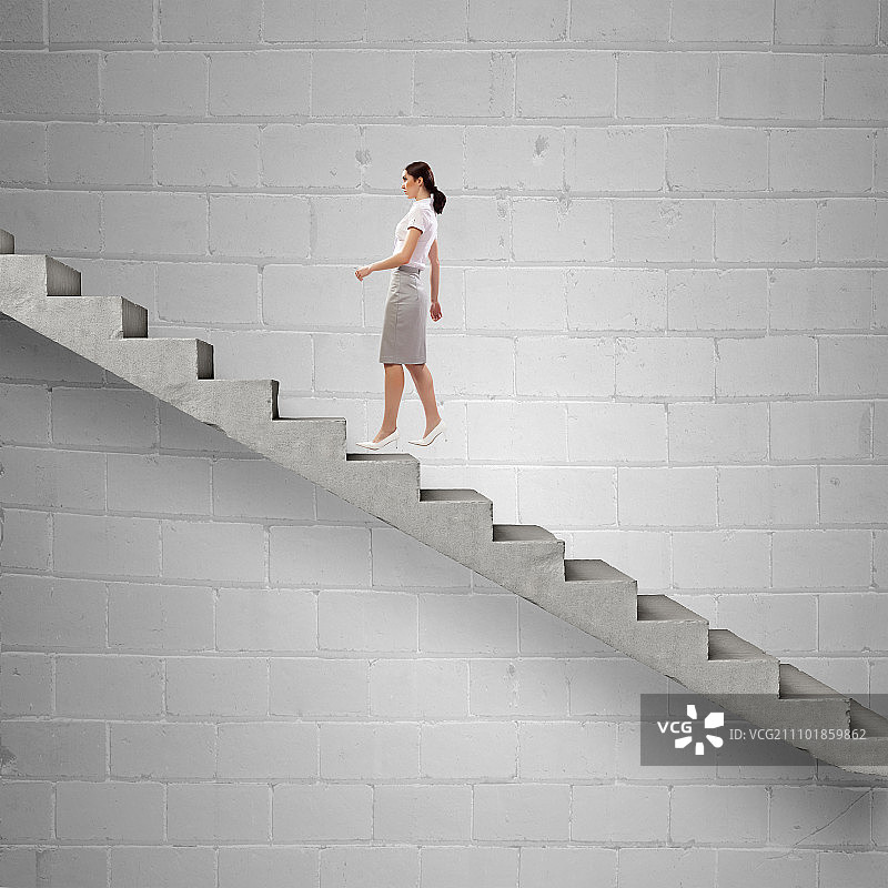 攀登职业阶梯。年轻的女企业家走上楼梯，代表着成功的理念图片素材
