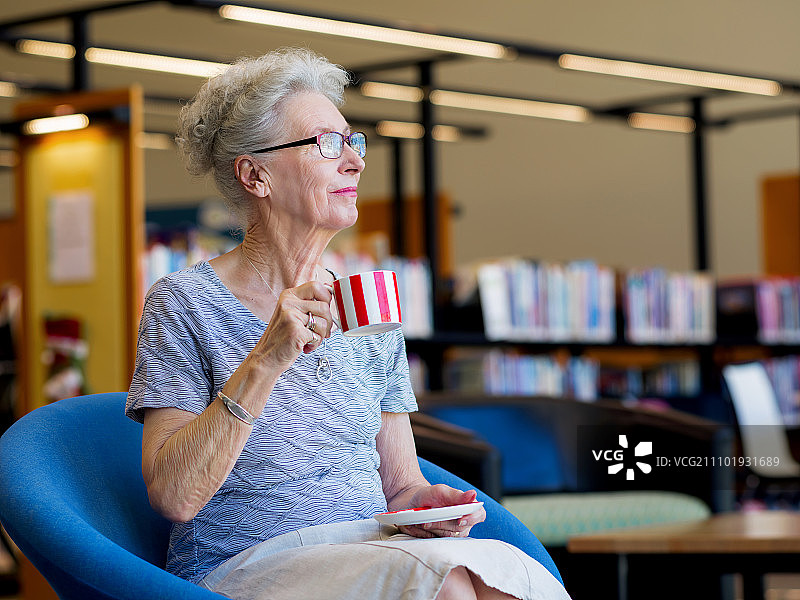 一位老太太在图书馆喝茶。喝几分钟茶图片素材