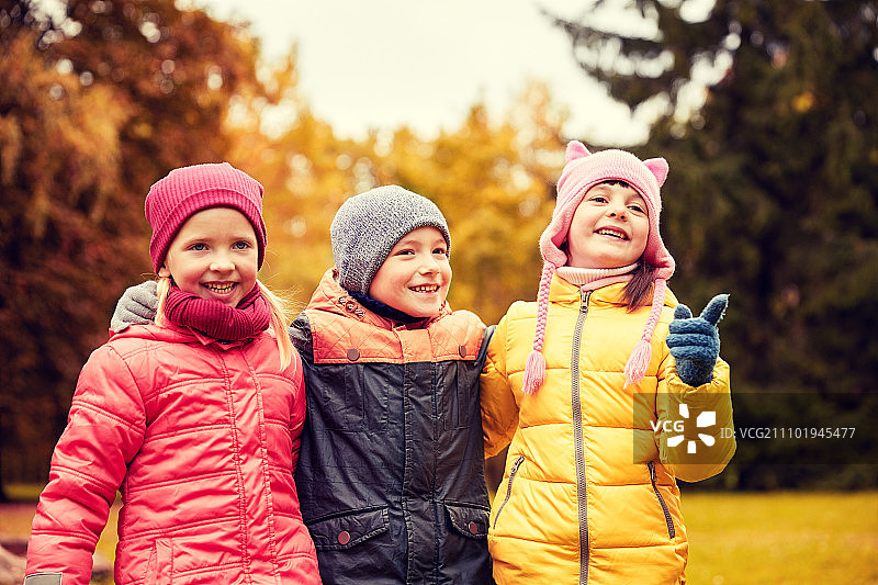 童年，休闲，友谊和人的概念——一群快乐的孩子在秋天的公园里拥抱和指着什么东西图片素材