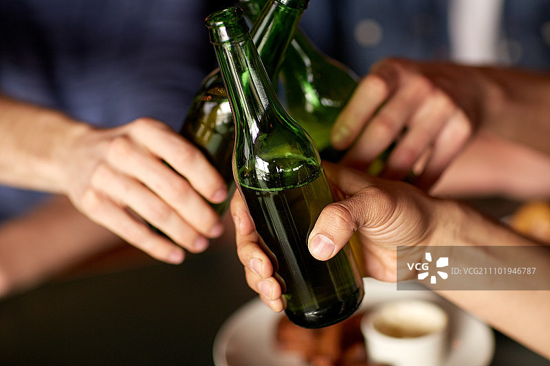 人们，男人，休闲，友谊和庆祝概念-近距离男性朋友喝啤酒和在酒吧或酒吧碰杯图片素材