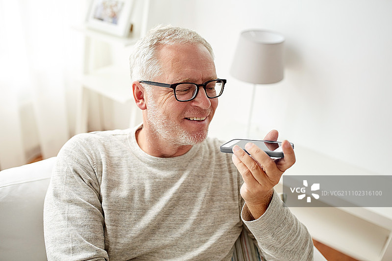 技术，人，生活方式和沟通概念-快乐的老年人使用语音命令记录器或打电话在家里的智能手机图片素材