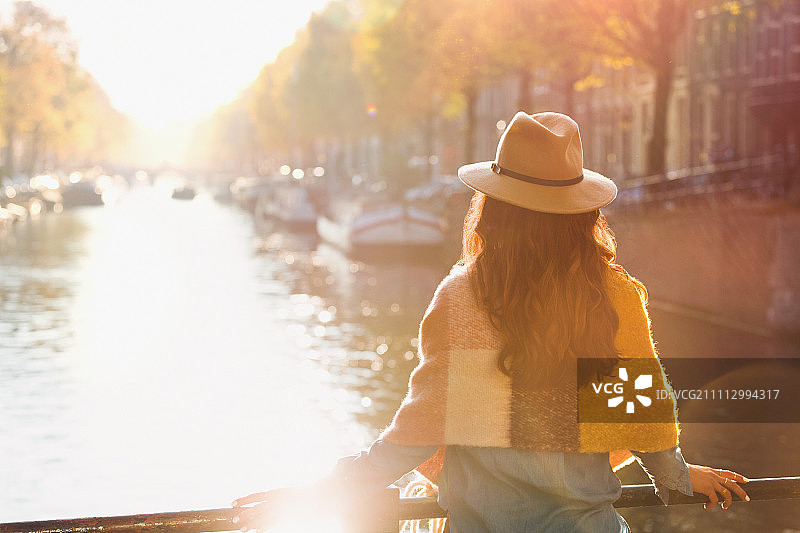 女人看着阳光明媚的秋天运河的景色，阿姆斯特丹图片素材