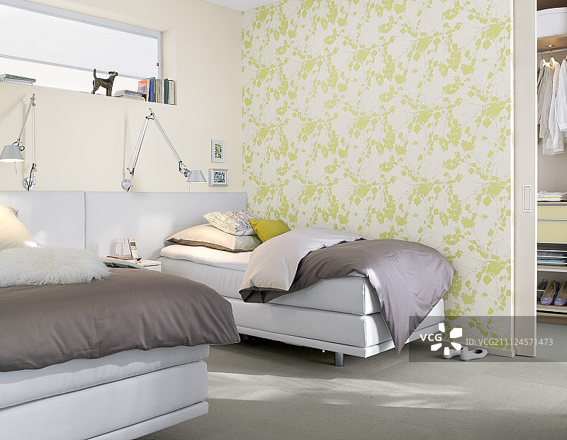 卧室有一张双人床，旁边是白色和绿色图案的墙图片素材