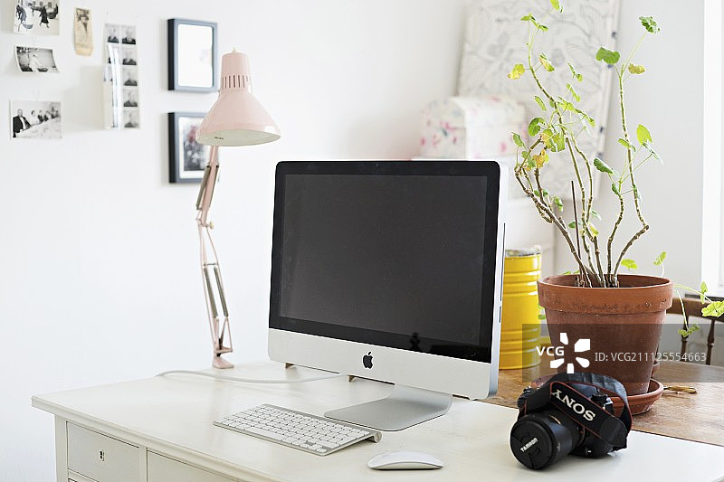 白色书桌上放着电脑、夹灯和盆栽图片素材