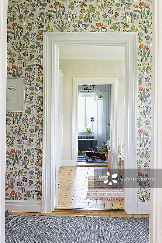 门厅墙上有花卉墙纸和远处房间里的玩具车景色图片素材