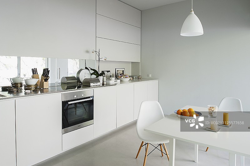 白色的用餐区，经典的家具和现代厨房柜台带窗户和集成屏幕图片素材