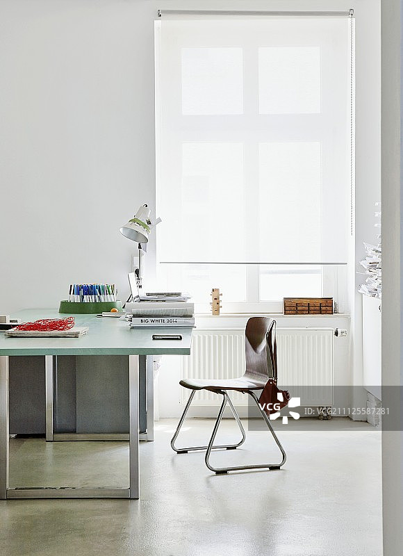 现代的书桌和复古的椅子旁边的窗户与白色滚动式百叶窗图片素材