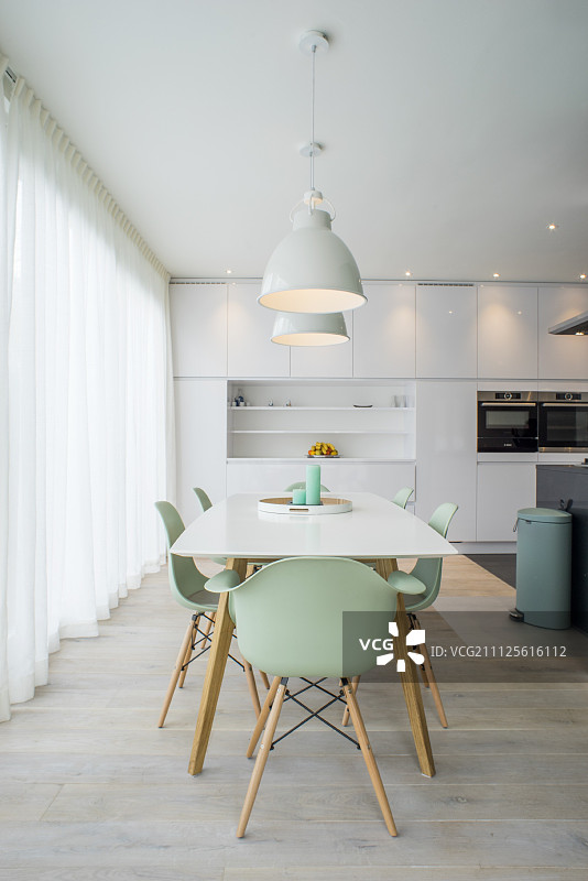 白色设计师厨房里的餐桌和薄荷绿贝壳椅图片素材