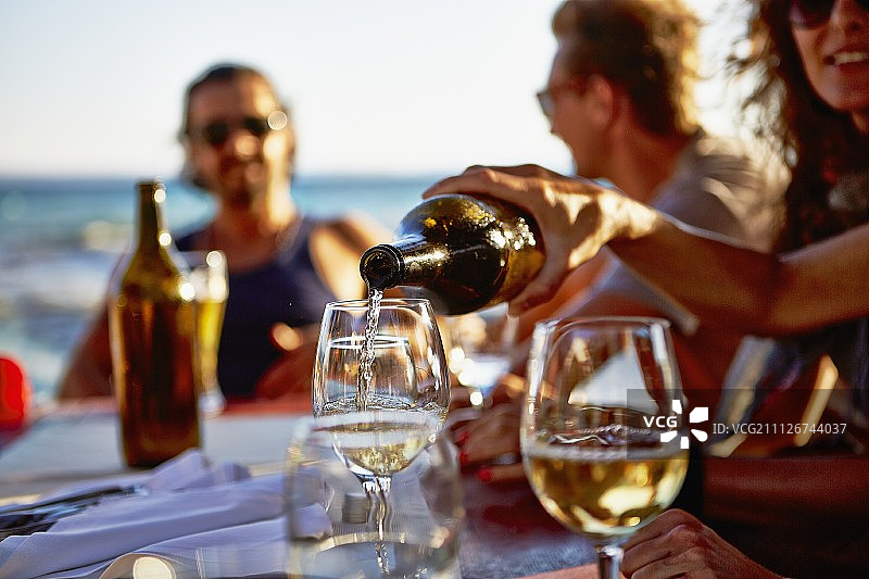 年轻人在一家俯瞰大海的餐厅里喝酒图片素材