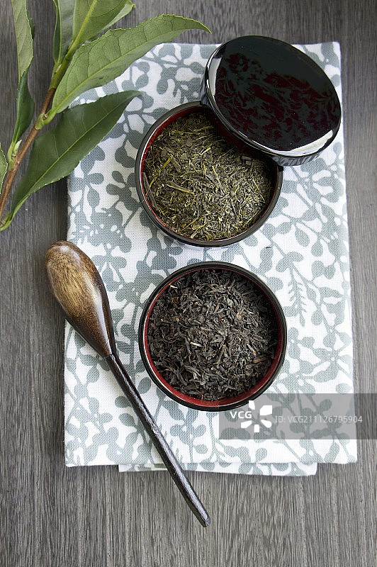 木制茶碗，有绿茶和红茶的叶子图片素材
