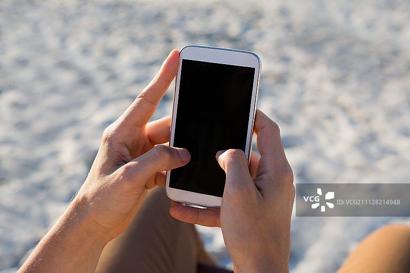 在海滩上用手机的男人的剪刀手图片素材