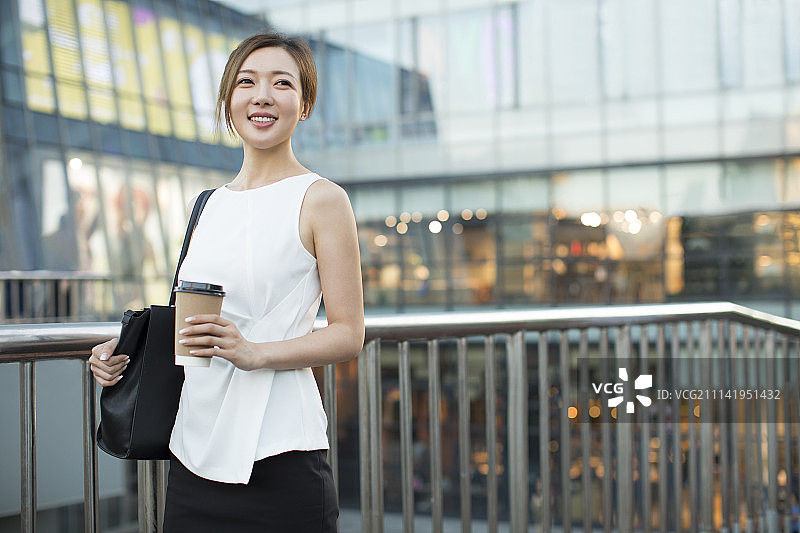 自信的年轻商务女子拿着一杯咖啡图片素材