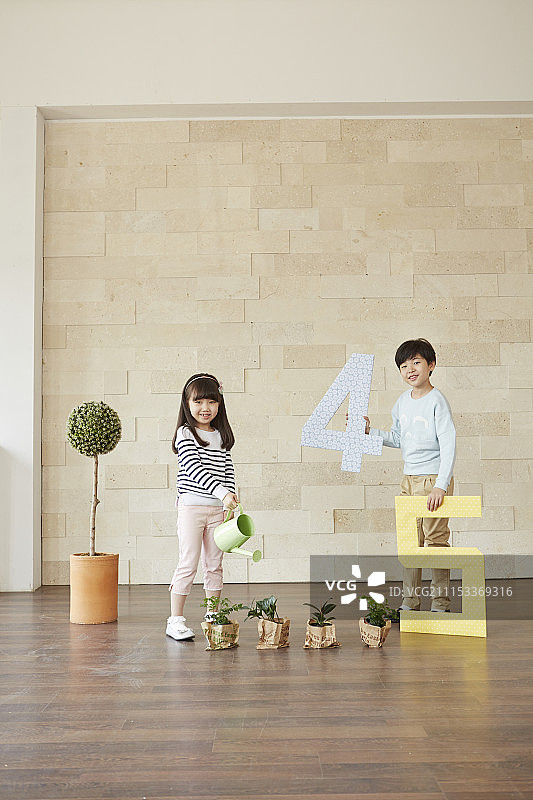 小男孩抱着4、5岁的小女孩在给植物浇水图片素材