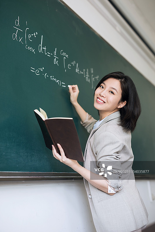 在黑板上写字的年轻女教师图片素材