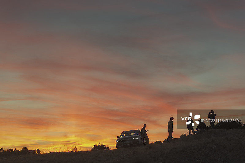 一群朋友的剪影附近的汽车在日落在自然的设置图片素材