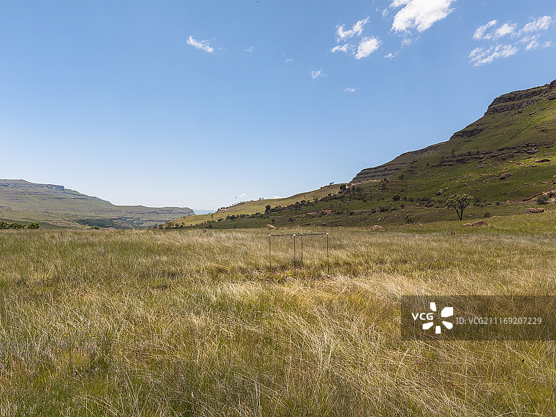 一条穿过长满草的山谷的土路，四周群山环绕图片素材