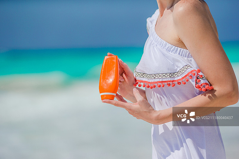 海滩上女性手中的防晒霜瓶子。图片素材