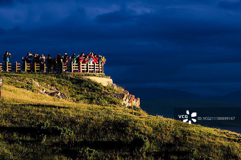 在巴音布鲁克草原观景台上观看落日的游客图片素材