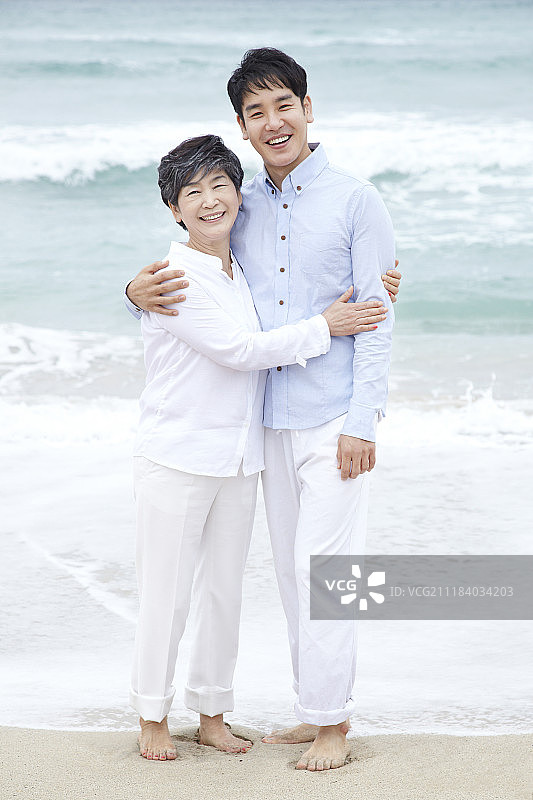 母亲和儿子在海滩上拥抱的照片图片素材