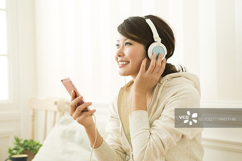 年轻女子用耳机和智能手机听音乐图片素材