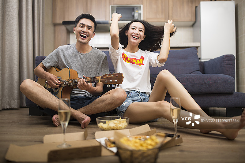 快乐的情侣在客厅演奏吉他图片素材
