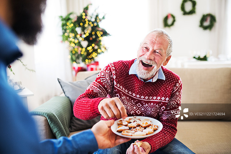 一个男人在圣诞节的时候在家里给他的老父亲饼干。图片素材