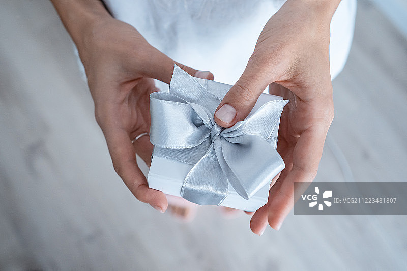 女人手握礼品盒与白色蝴蝶结，特写图片素材