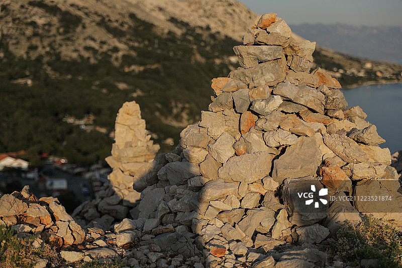 日落时山上的手工石头堆图片素材