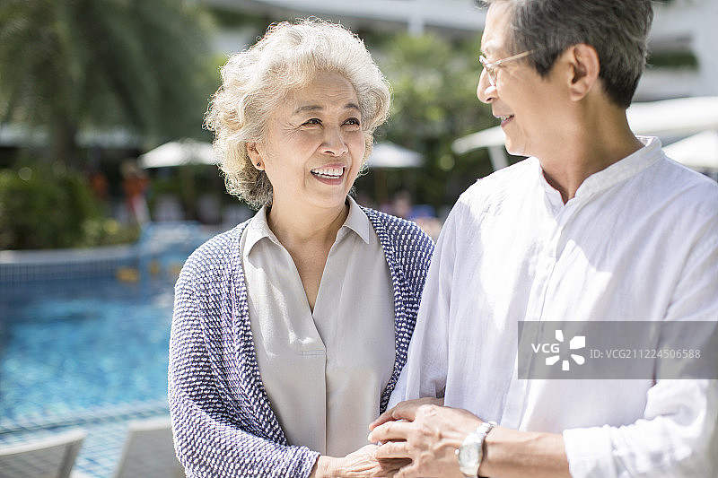 快乐的老年夫妇在泳池边散步图片素材