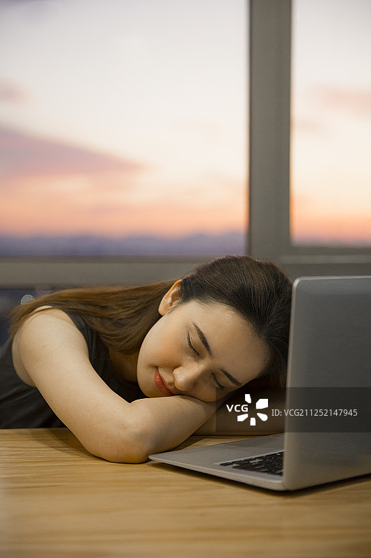 青年女子在会议室使用笔记本电脑工作疲劳的睡觉加班图片素材