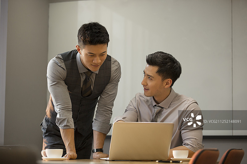 商务青年男子使用笔记本电脑在公司会议室讨论工作图片素材