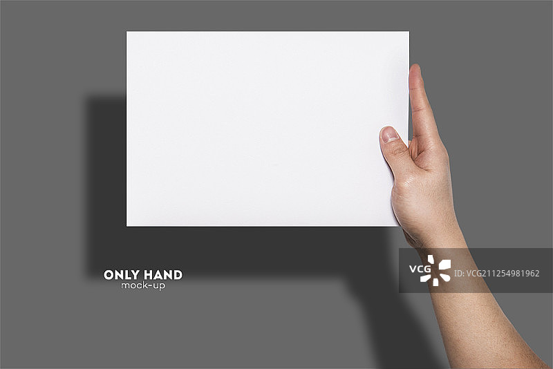 手握一张空白纸，孤立在一个灰色的背景图片素材