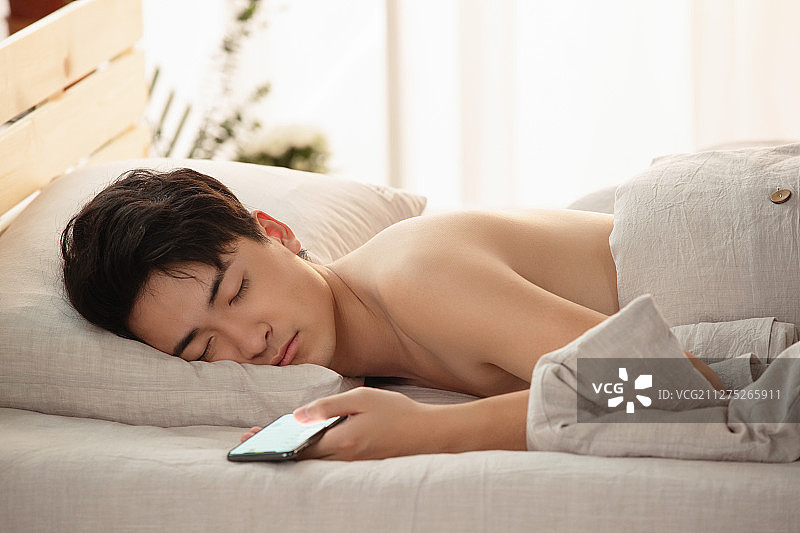 玩手机玩到睡着的年轻男人图片素材