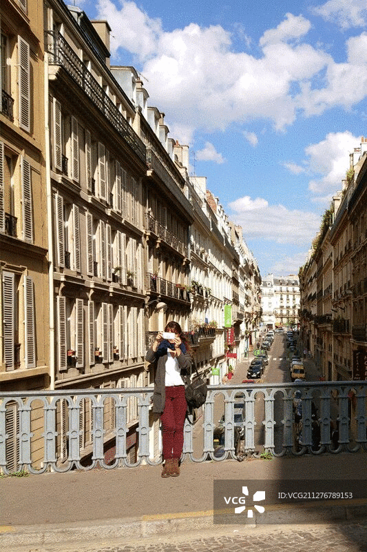 年轻的成年女子在巴黎街头拍摄视频，3D立体效果图片素材