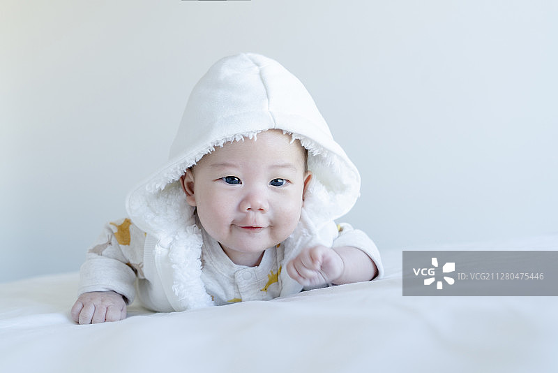 穿白色连帽马甲的宝宝俯卧表情图片素材