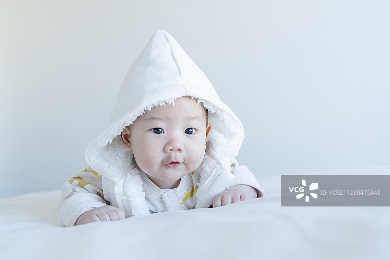 穿白色连帽马甲的宝宝俯卧表情图片素材