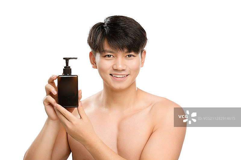 白色背景里的手里拿着化妆品瓶子的亚洲男士面部特写，化妆护肤图片素材