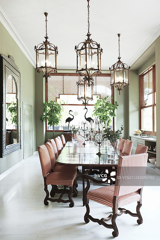 明亮的餐厅里，长餐桌和椅子上优雅的烛台图片素材