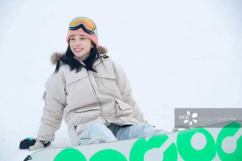 踩着单板坐在雪地上的青年女人图片素材